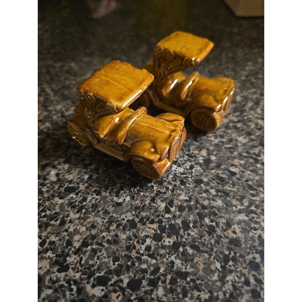 two vintage ceramic figurines shaped like antique cars, likely Model T's or...